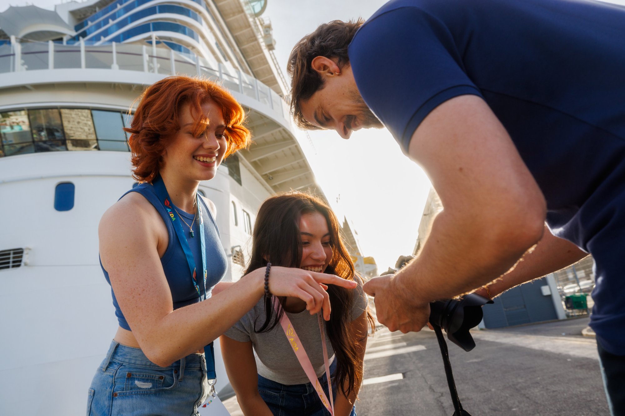 Die Freundinnen betrachten die Fotos, die der Fotograf vor dem Schiff von ihnen gemacht hat.