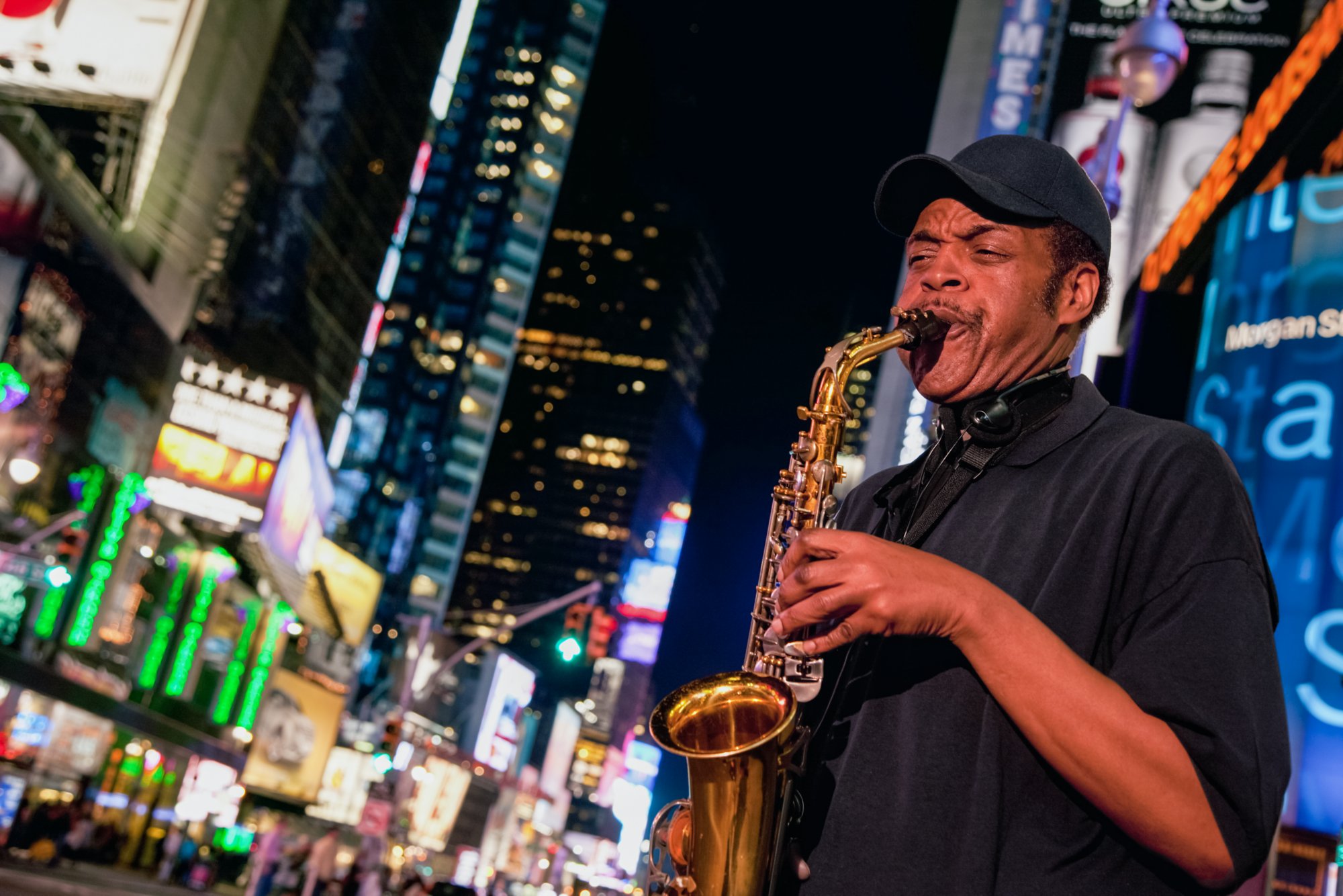 Ein Saxophonspieler auf dem Broadway am Times Square bei Nacht. New York, USA