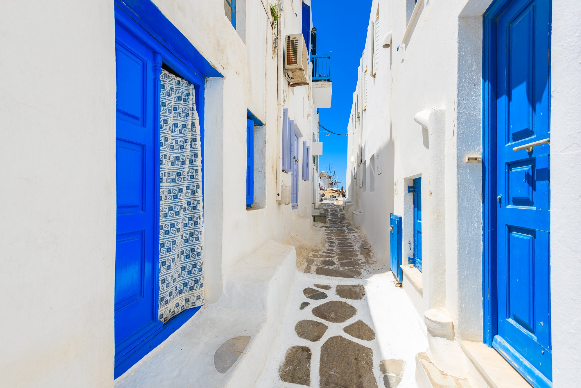 A view of whitewashed street with blue doors in Mykonos town, Cyclades islands, Greece