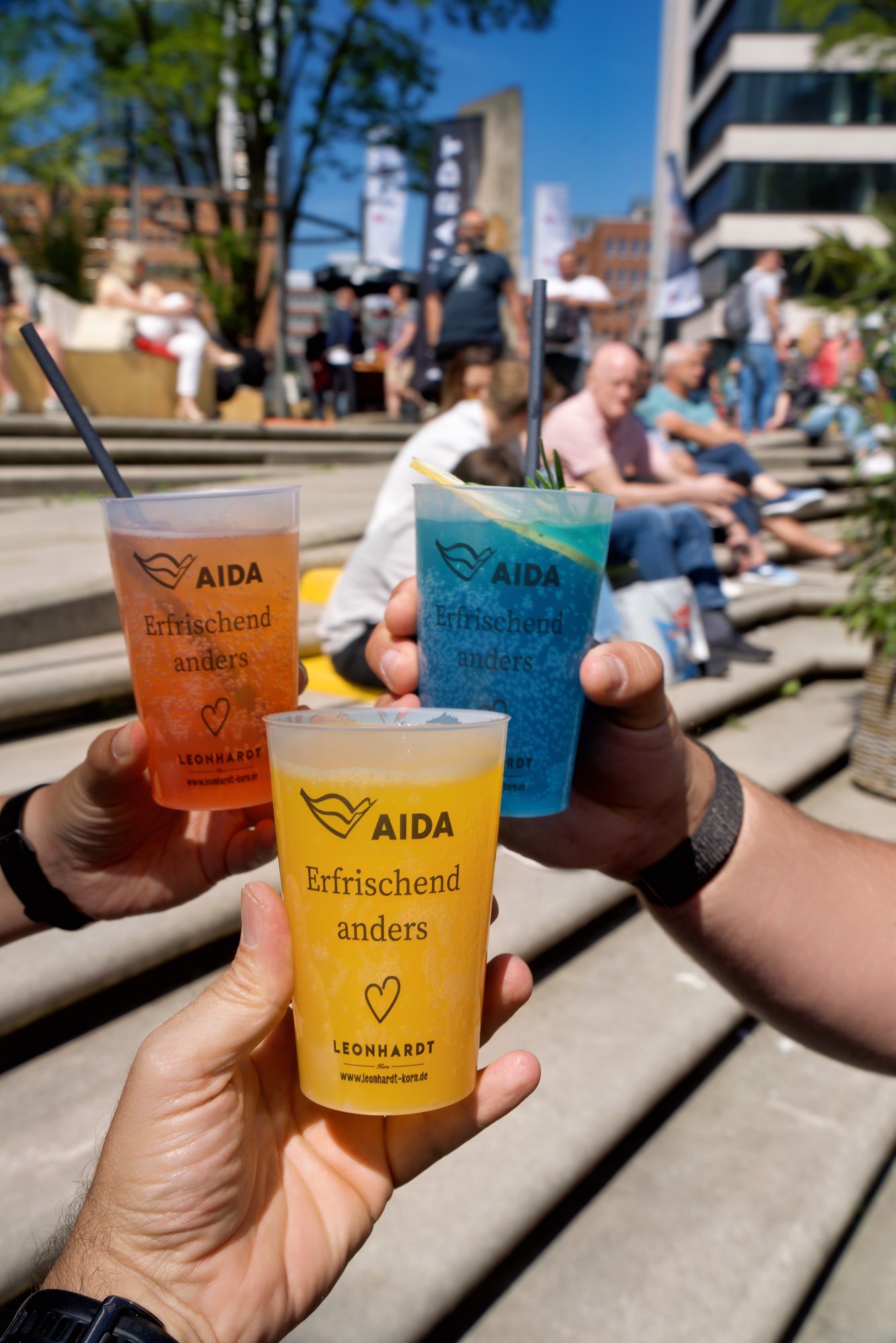 Hafengeburtstag Hamburg man sieht die Hände von Menschen, die mit bunten AIDA Bechern anstoßen