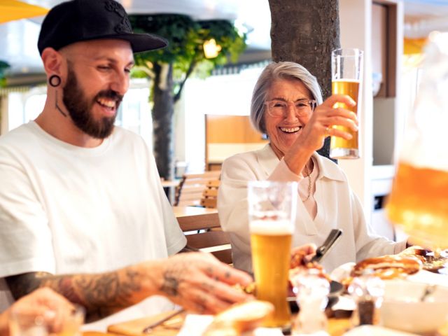 Ein Mann und eine FRau sitzen im Brauhaus bei Essen und Bier