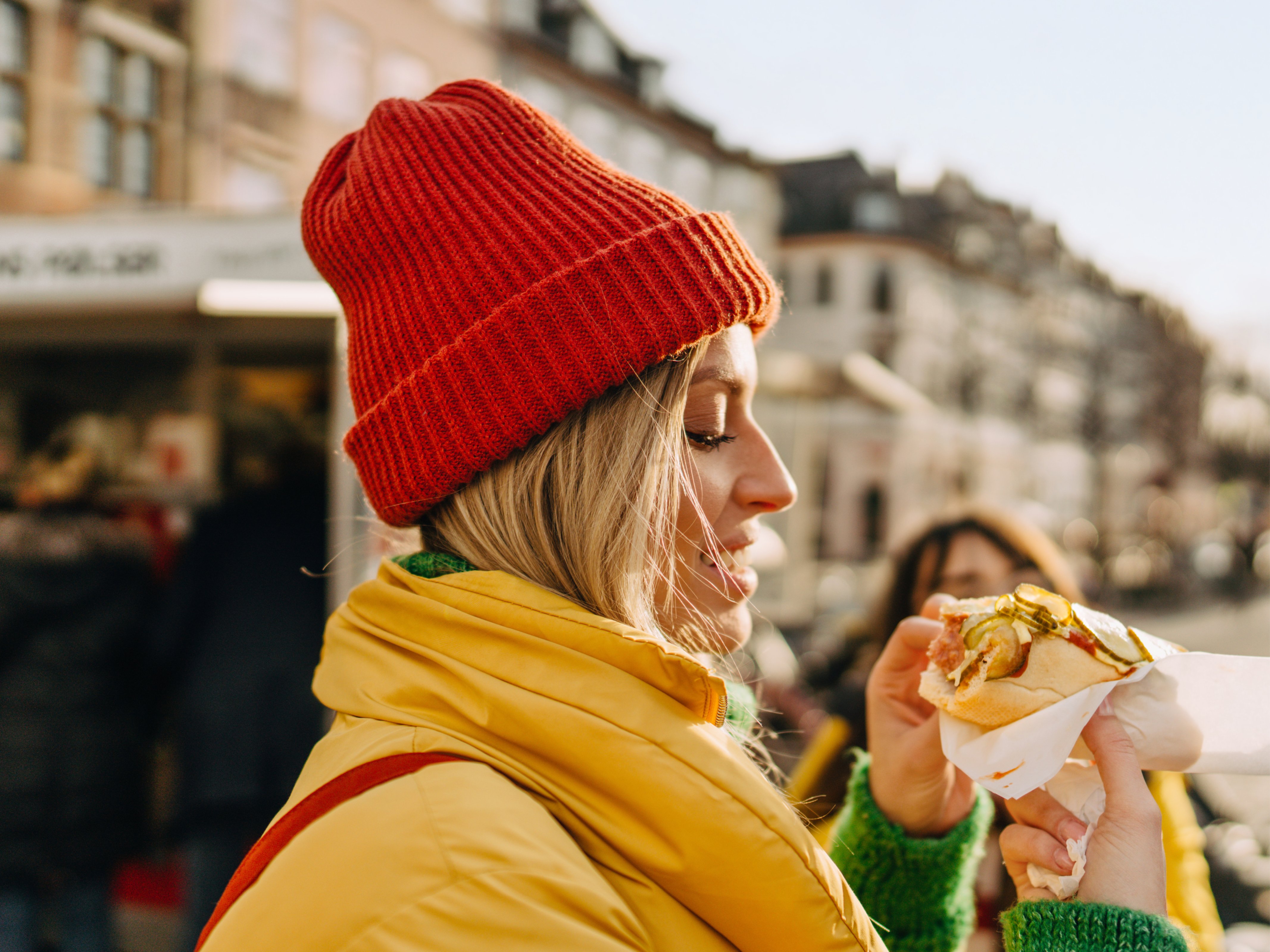 Frau mit roter Mütze isst HotDog in Kopenhagen 