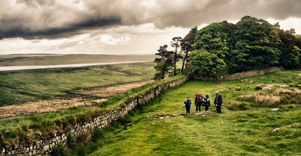 A group of hikers walk along Hadrian's Wall in Northern England.  With dramatic processing.