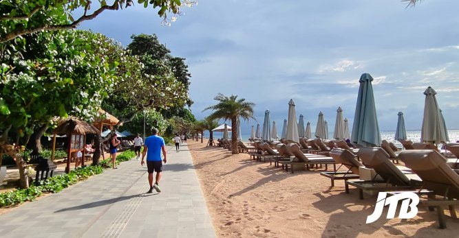 TOUR OPERATOR GATEWAY - A sunny path along Sanur Beach with shaded loungers and lush greenery.