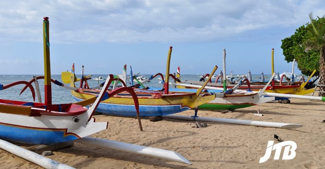 TOUR OPERATOR GATEWAY - Colorful traditional fishing boats line the sandy shore of Sanur Beach.