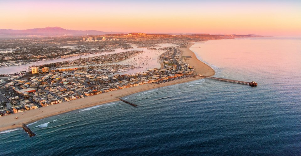 A wide angle view of the entire Newport Beach area including the harbor and Newport Beach Pier shot from an altitude of about 2000 feet over the Pacific Ocean at dusk.