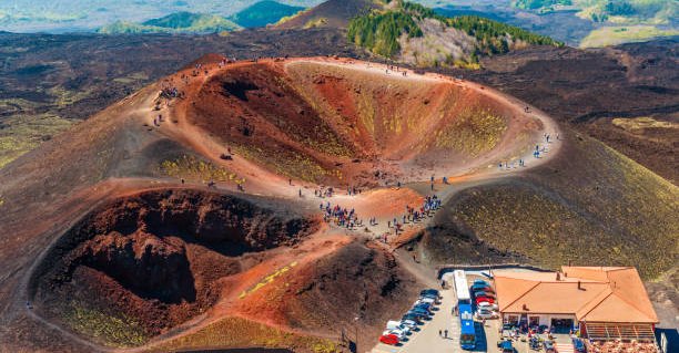 Stunning view at the volcanic crater and groups of tourists walking around it. Mount Etna, Sicily, Italy.