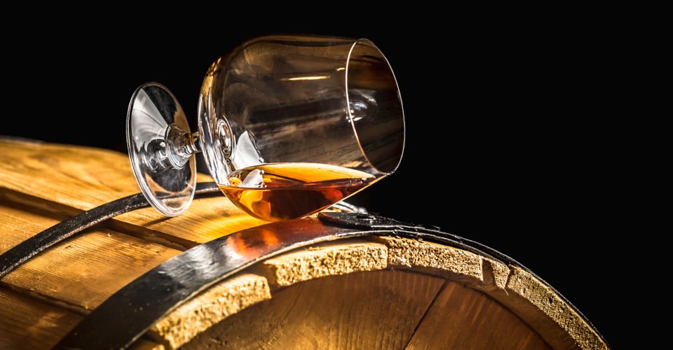 Glass of cognac on the old wooden barrel.