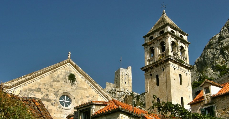 View of the old pirate town of Omis. The bell tower of St. Michael, the fortress Mirabella - and old pirate view tower, and old traditional stone house. Horizontal color photo. 