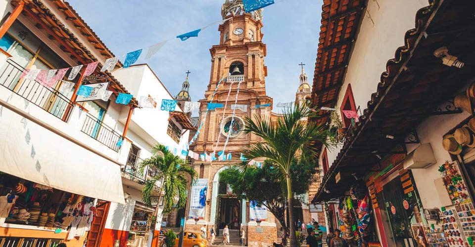 Puerto Vallarta, Mexico - December 28, 2016: Our Lady of Guadalupe Parish sits on a busy street filled with tourists and souvenir vendors.