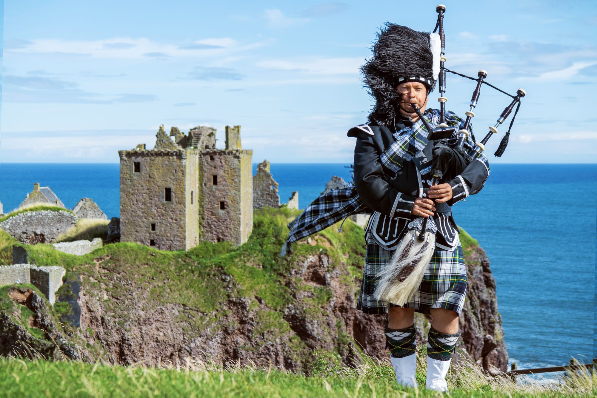 Traditioneller schottischer Dudelsackspieler in voller Tracht auf Schloss Dunnottar in Stonehaven.