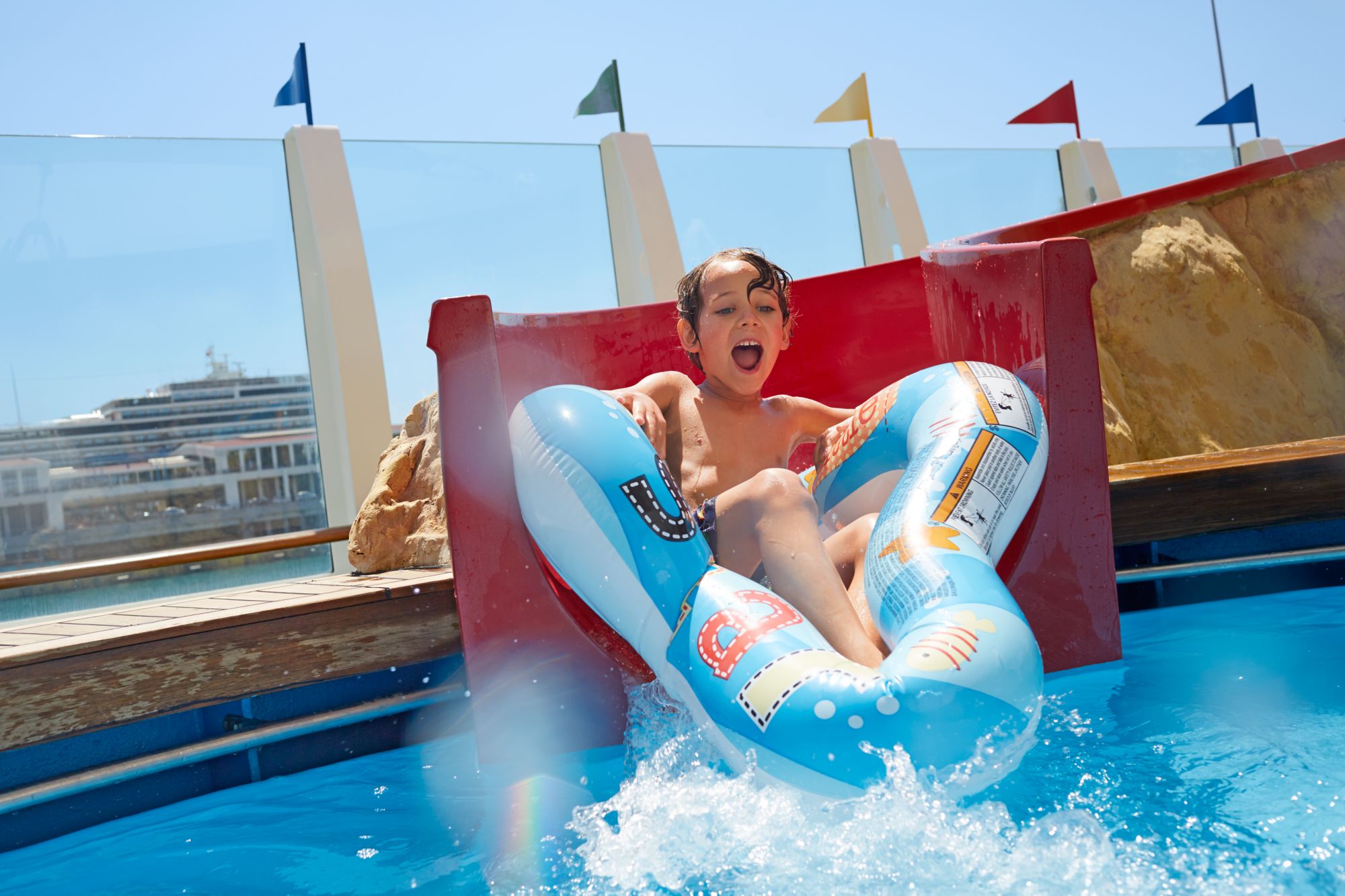 Kind rutscht mit Reifen in Pool auf Kreuzfahrtschiff