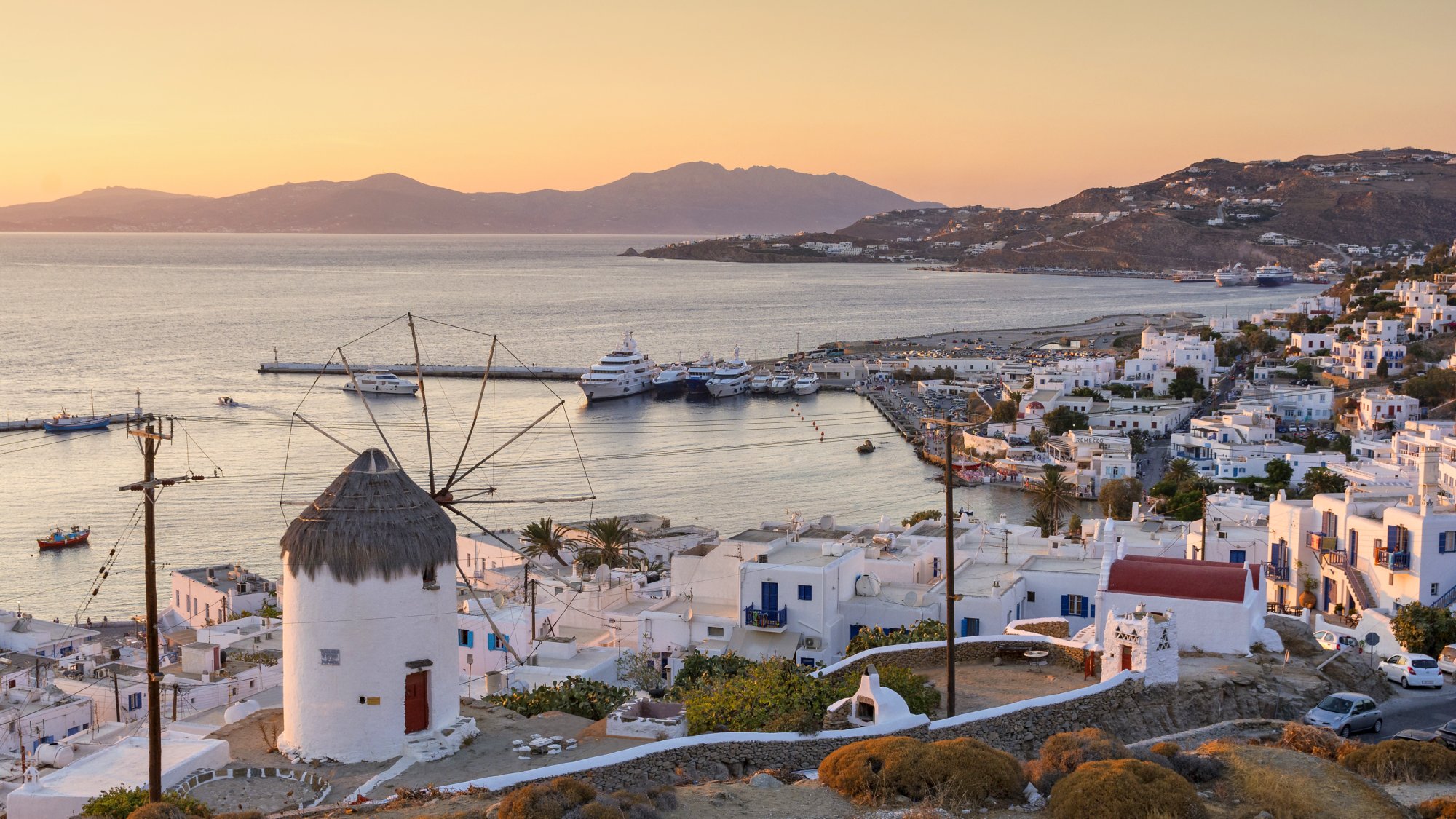 view of Mykonos, windmill and port with cruise ship at sunset