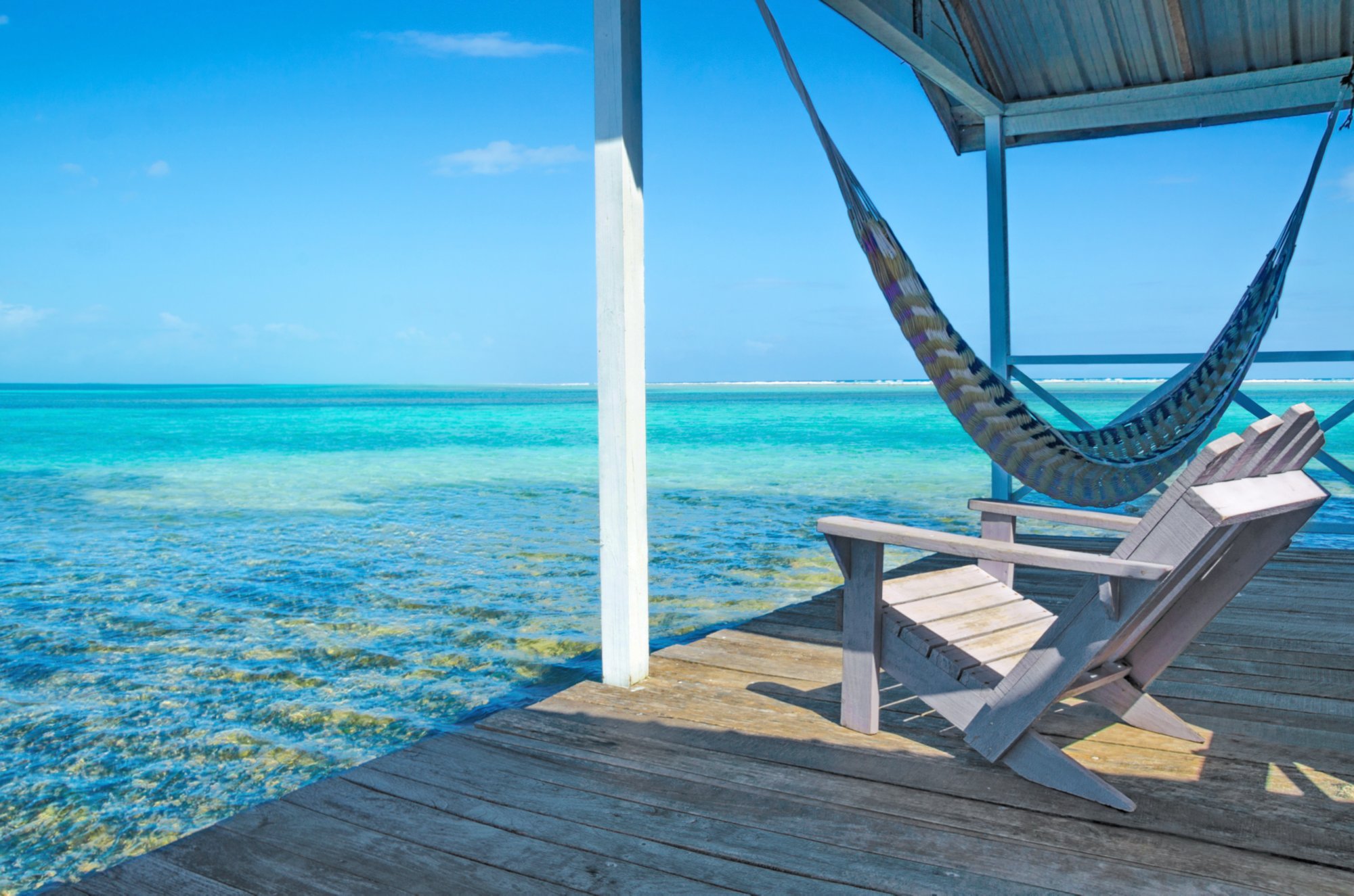 Hängematte und Liegestuhl auf einer Terrasse über dem blauen Meer