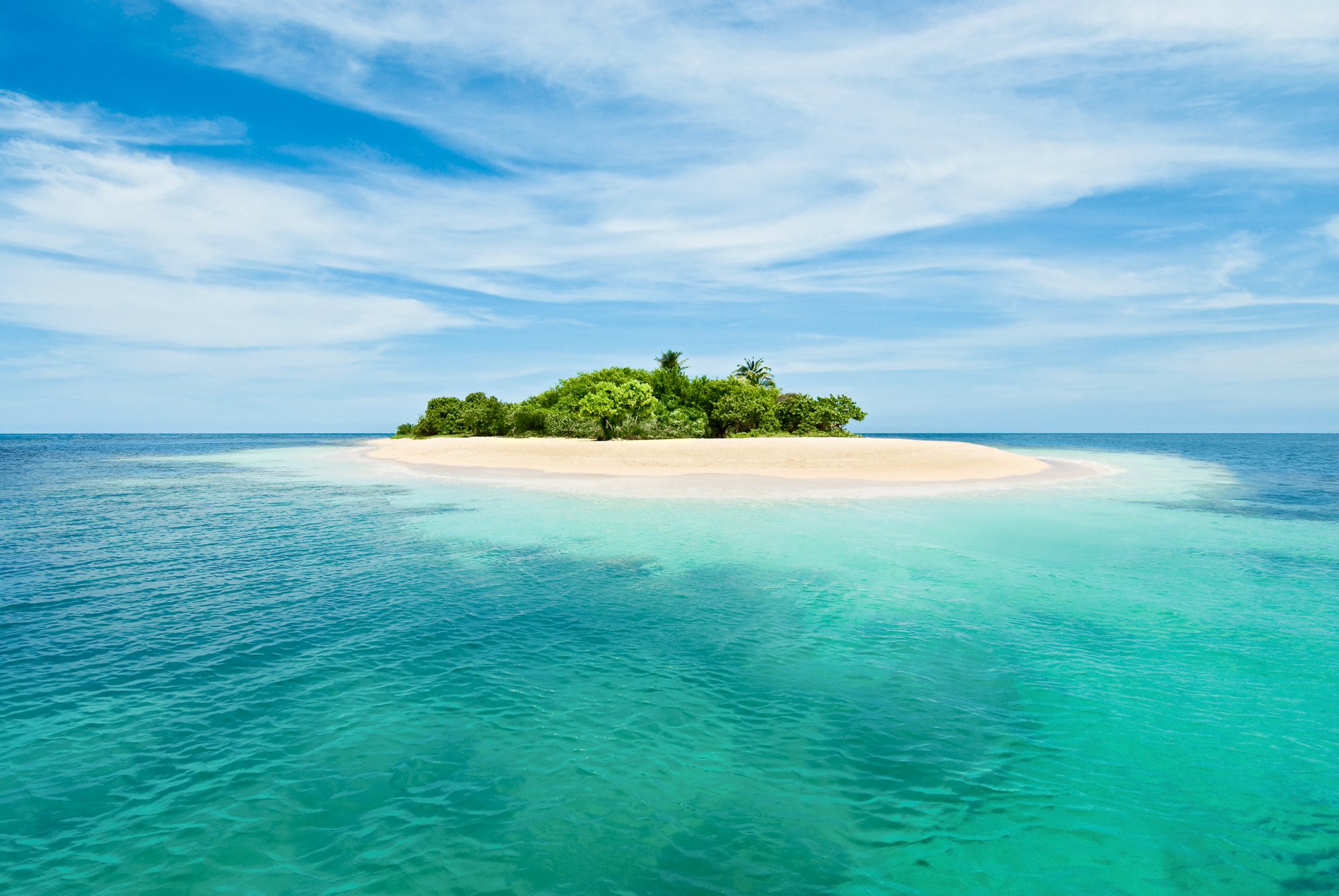 Small tropical desert island with turquoise waters and clear sky