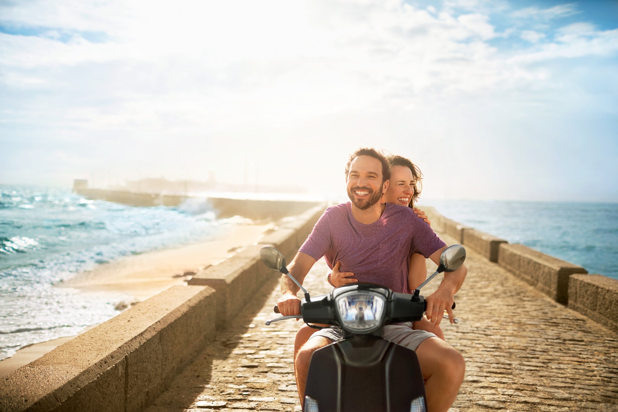 Paar fährt mit Vespa am Meer entlang