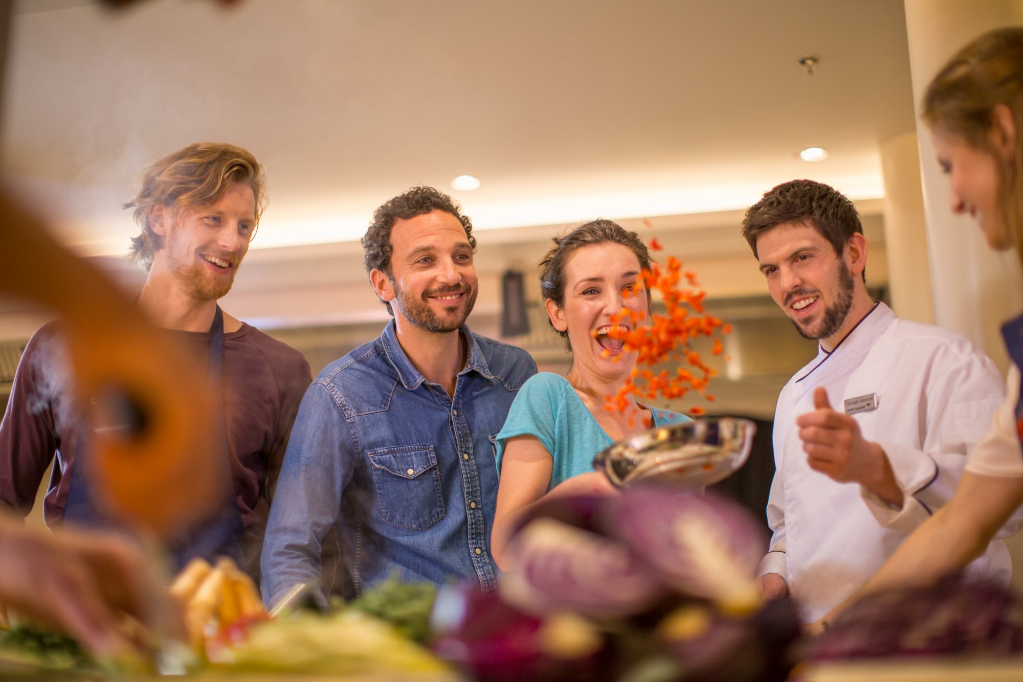 Zwei Männer und zwei Frauen kochen zusammen mit einem Koch