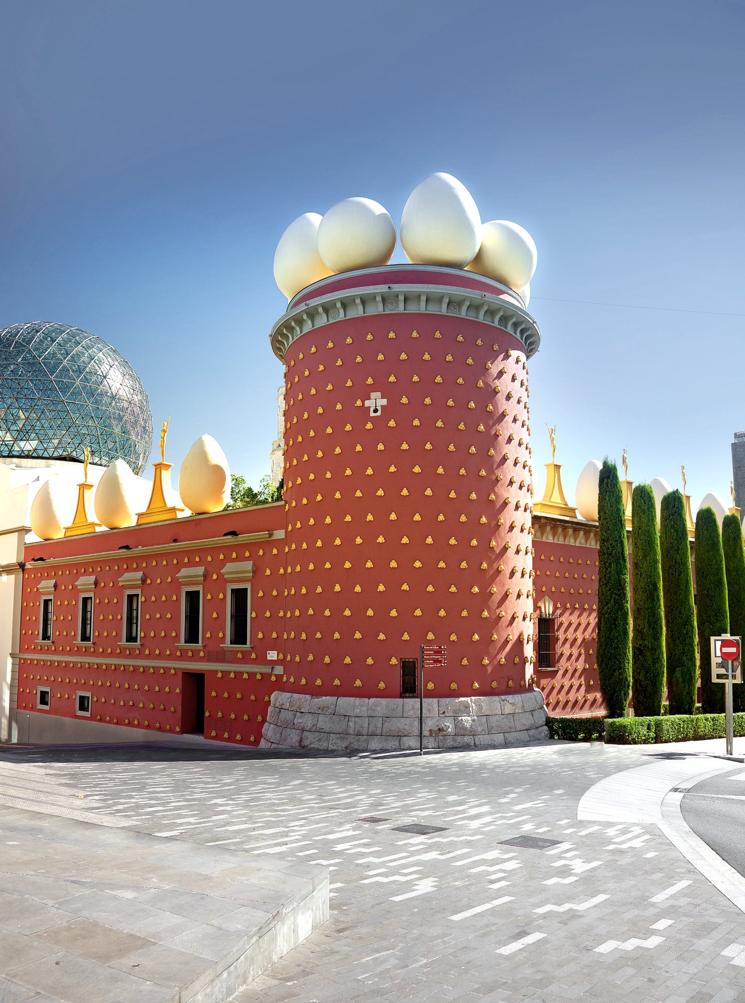 Künstlerische Architektur mit Eiern auf dem Dach – das Dalí-Museum nahe Palamós mit markanter Fassade und Zypressen.