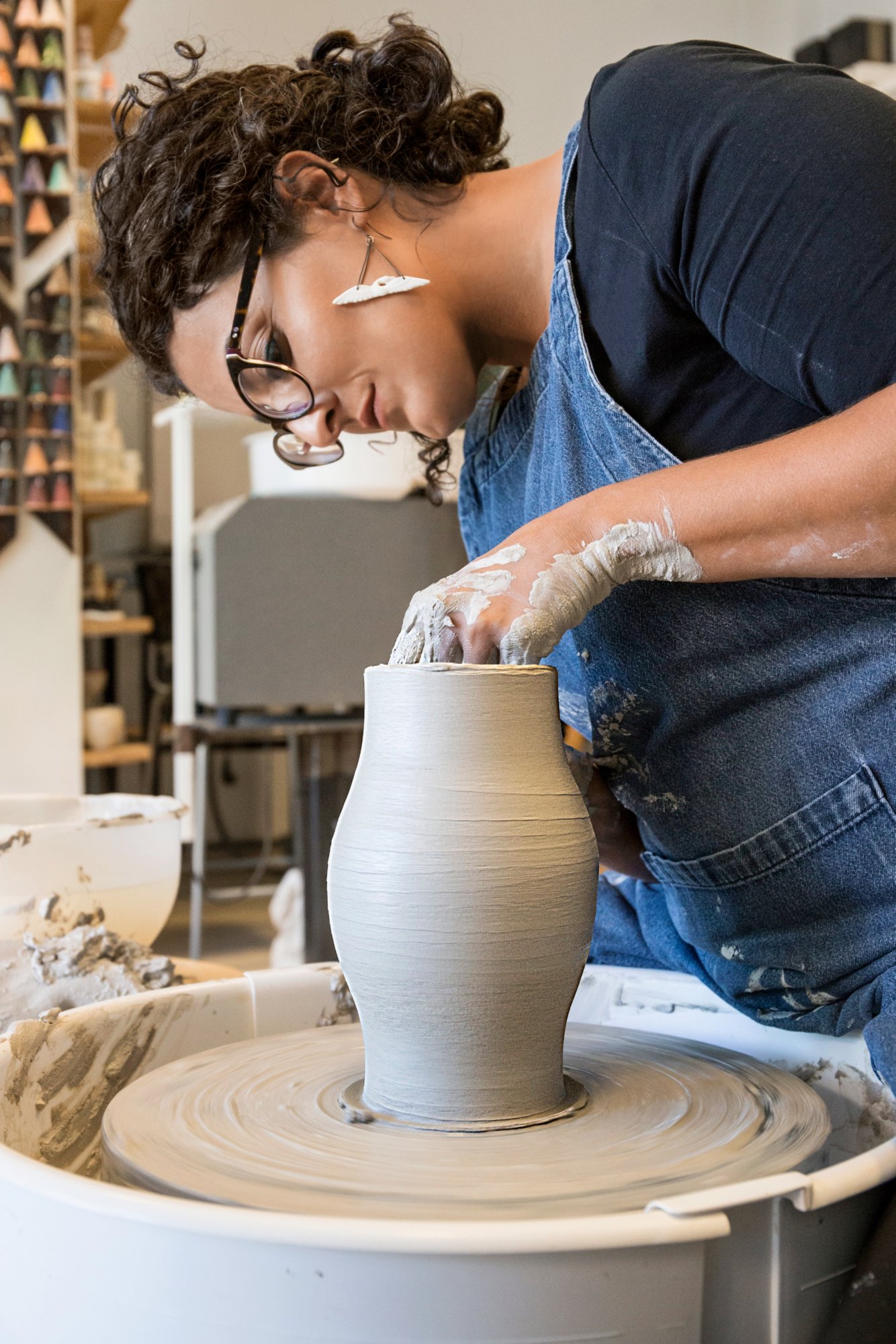 Woman working with a pottery wheel in her workshop