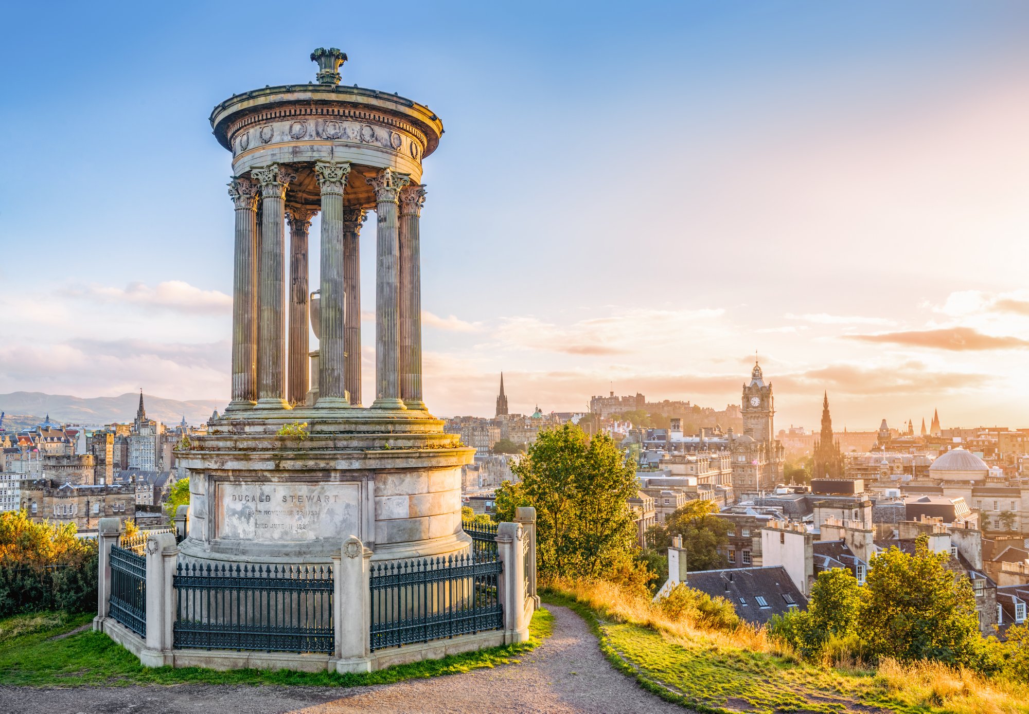 A view over central Edinburgh at sunset, taken from Calton Hill, with the stone memorial to  Dugald Stewart (1753 - 1828) in the foreground.