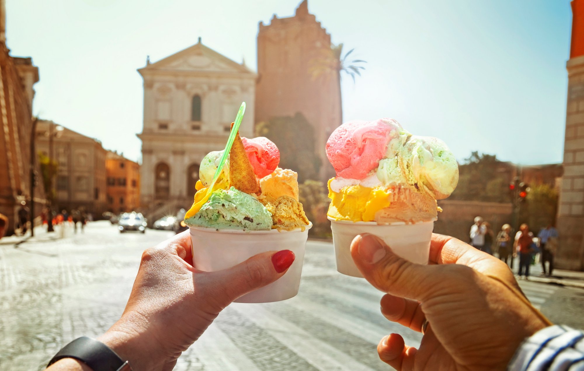 Couple with beautiful bright  sweet Italian ice-cream with different flavors  in the hands   on the square in Rome , Italy