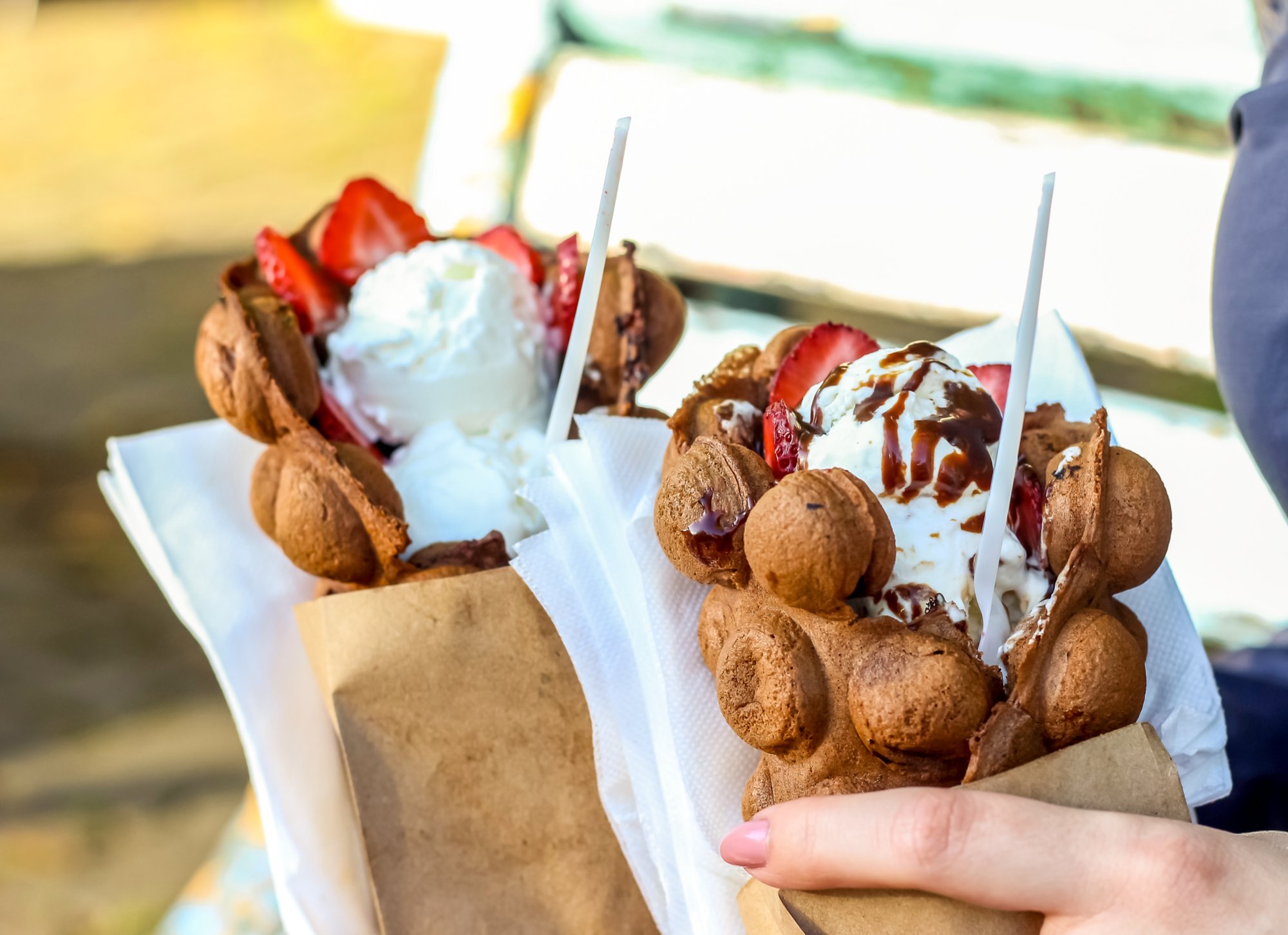 Bubble waffles with ice cream in woman hand. Close up. Street food. Decorative