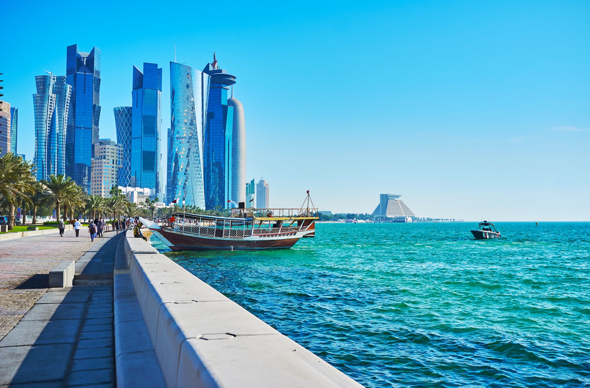 The pleasure boats at the coast of West Bay, the glass skyscrapers of Al Dafna business district are seen on background, Doha, Qatar.