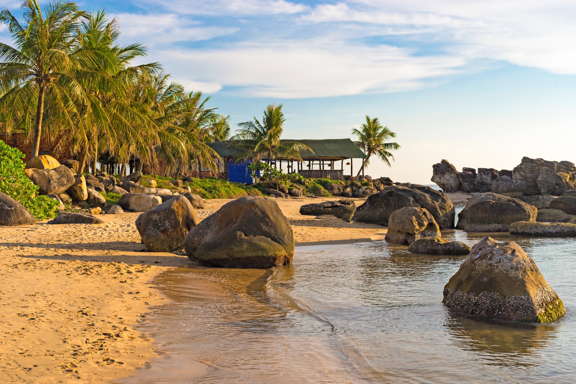 Seashore with stones in water on coastline at sunset on Long Beach of Phu Quoc island in Vietnam