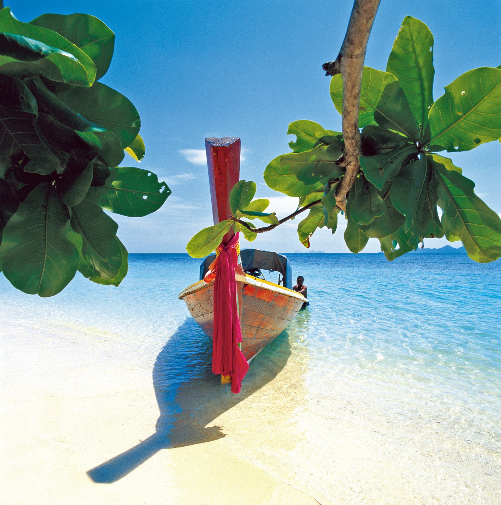 Long-tailed boat beached on a powdery white sandy beach on Kradan Island, Krabi Province, Thailand. 