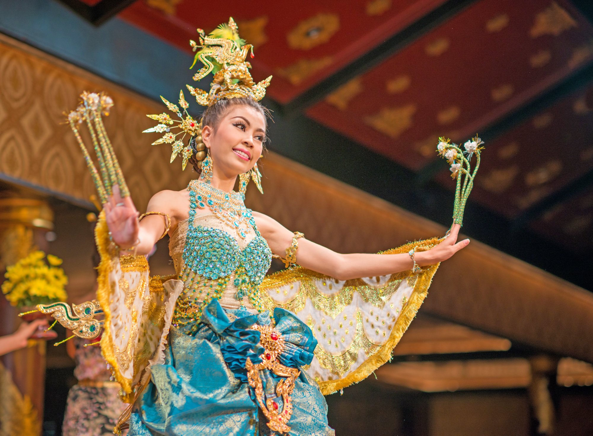 A beautiful thai dancer performs the Kinnaree Procession. Dressed as a half-bird-half-female creature the heroine brings good luck to her residents. Nikon D800e. 85mm 1.4 to catch the ambient light and mood. Copy space on the right.