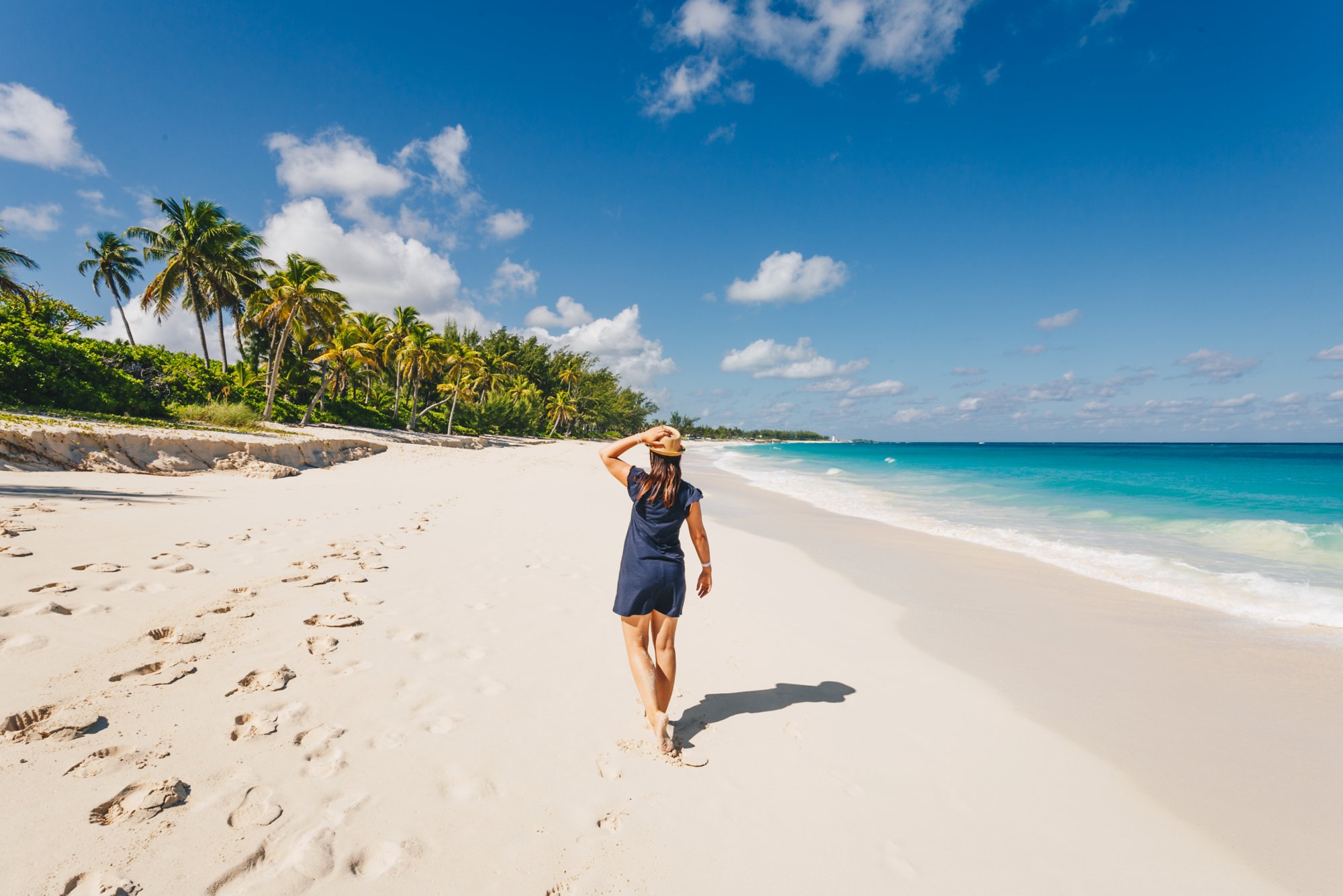 Frau läuft am Strand mit Palmen und Meer