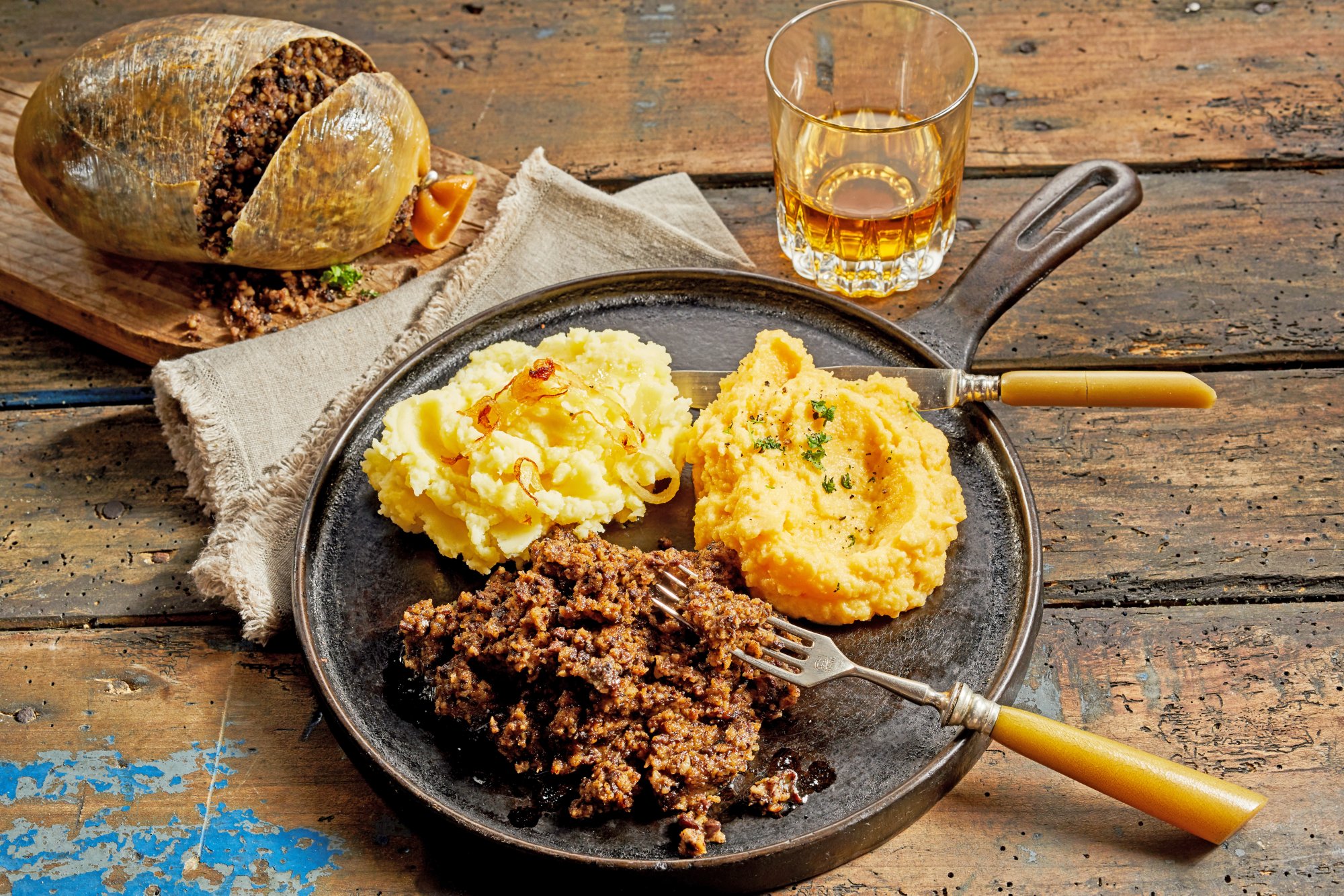 Rustic meal of haggis, neeps and tatties served with a tumbler of whisky to celebrate Robert Burns Supper in a high angle view