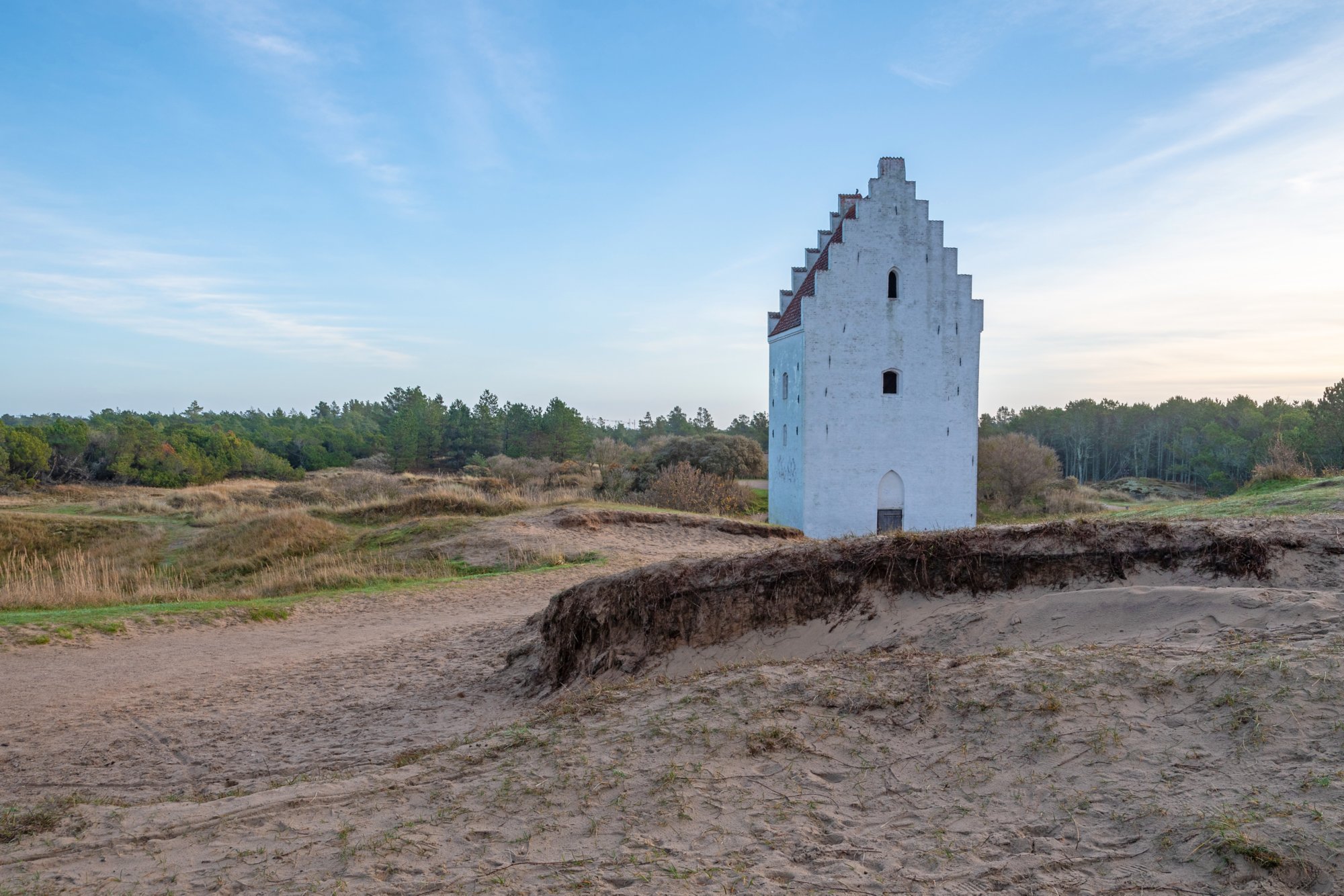 Der weiße Turm der versandeten Kirche (Den Tilsandede Kirke) ragt aus der Dünenlandschaft bei Skagen, Dänemark, unter klarem Himmel hervor.