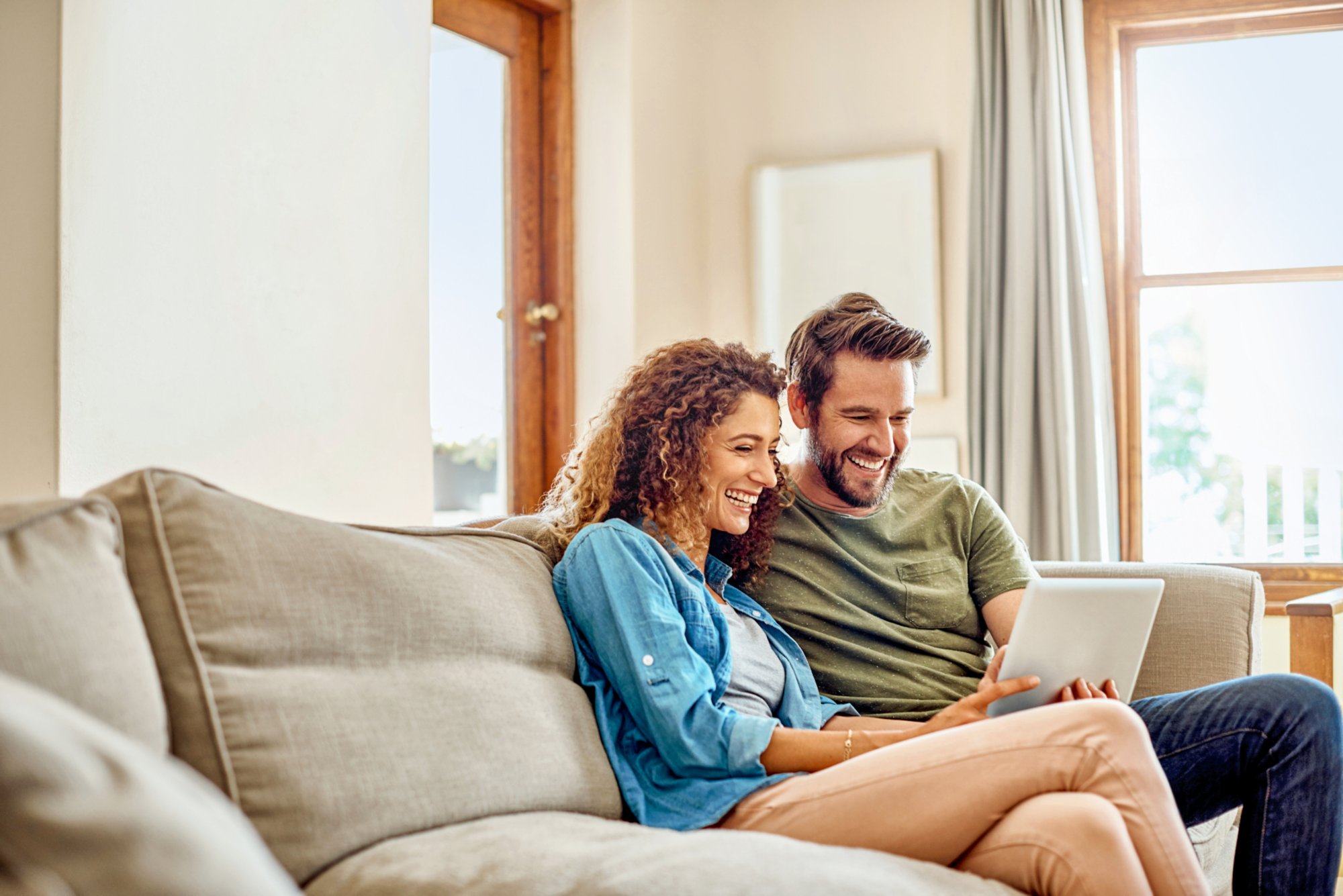 Shot of a happy young couple using a digital tablet together on the sofa at home