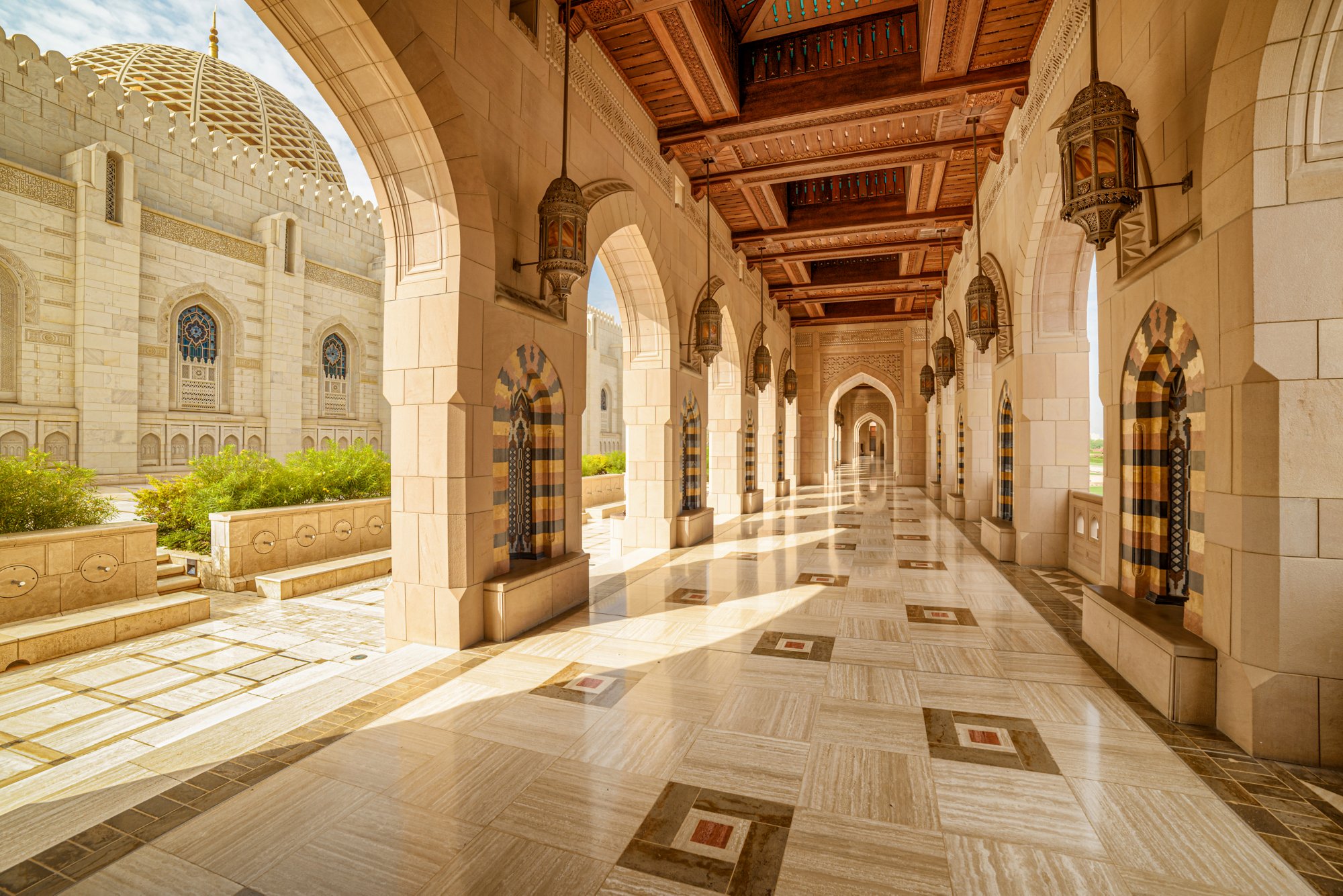 Muscat, Oman - 17 October, 2018: View of deserted arched passageway at the Sultan Qaboos Grand Mosque. Islamic architecture. The Muslim place is a popular tourist attraction of the Middle East.