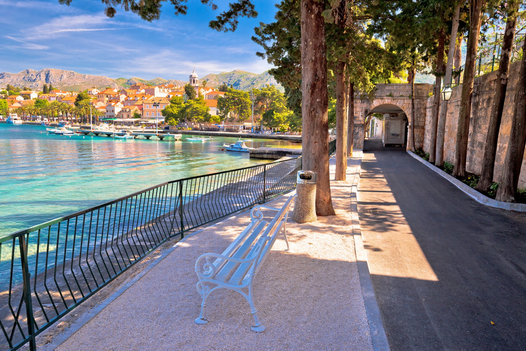 Uferpromenade vor Türkisfarbenem Wasser mit Stadtblick