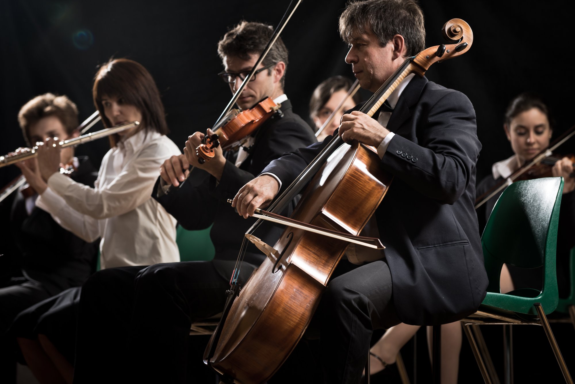 Symphony orchestra on stage, violins, cello and flute performing.