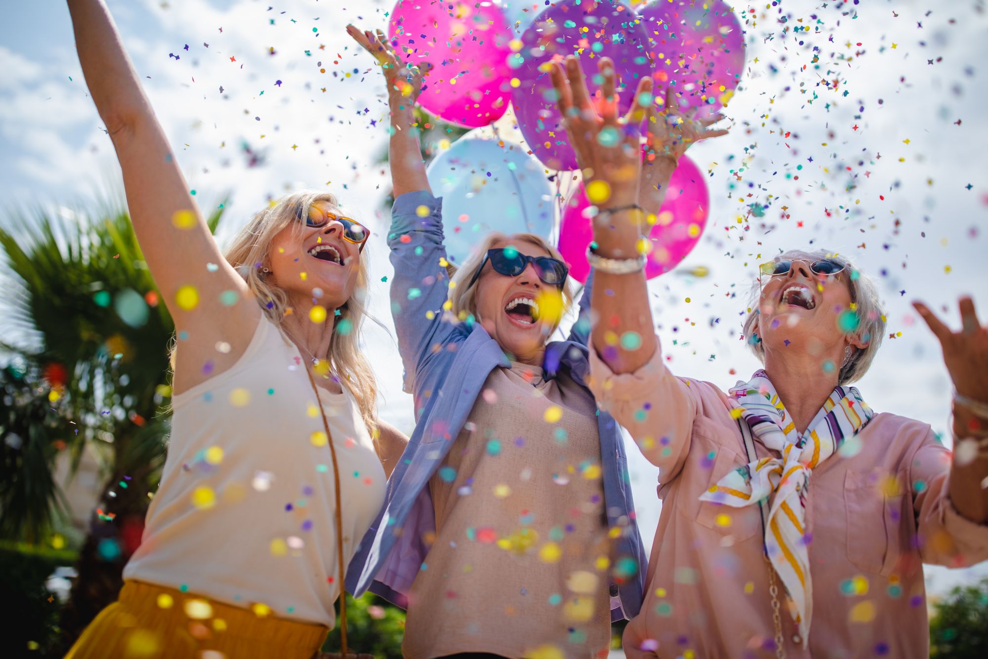 Eine Gruppe Frauen jubeln, halten Luftballons und werfen Konfetti in die Luft
