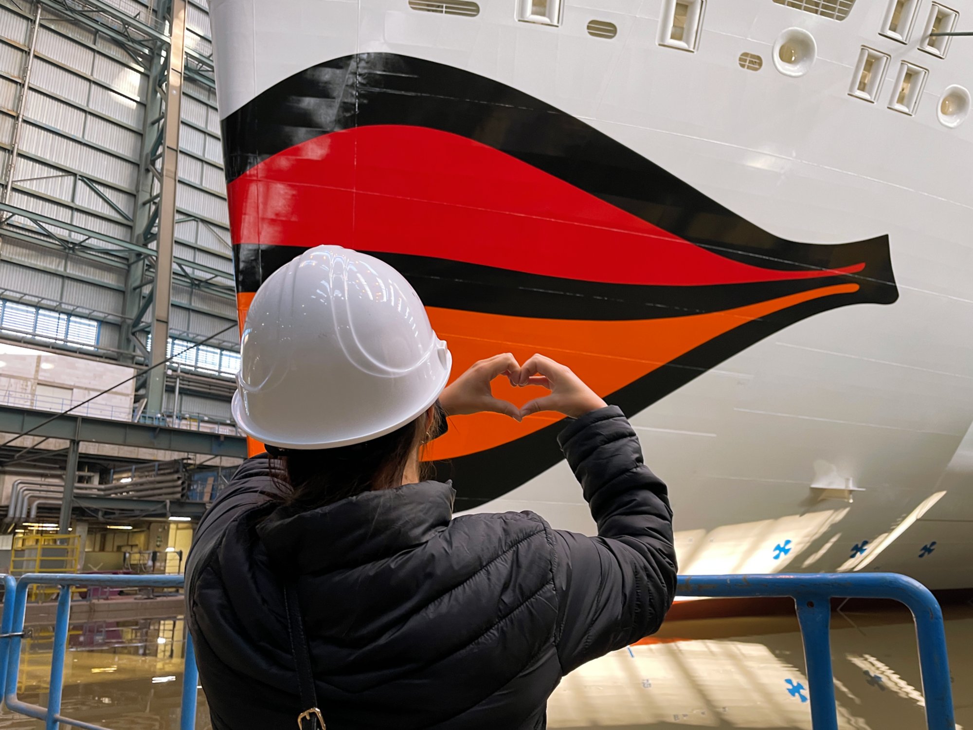 Person in der Werft formt Herz mit den Händen vor dem AIDA Kussmund