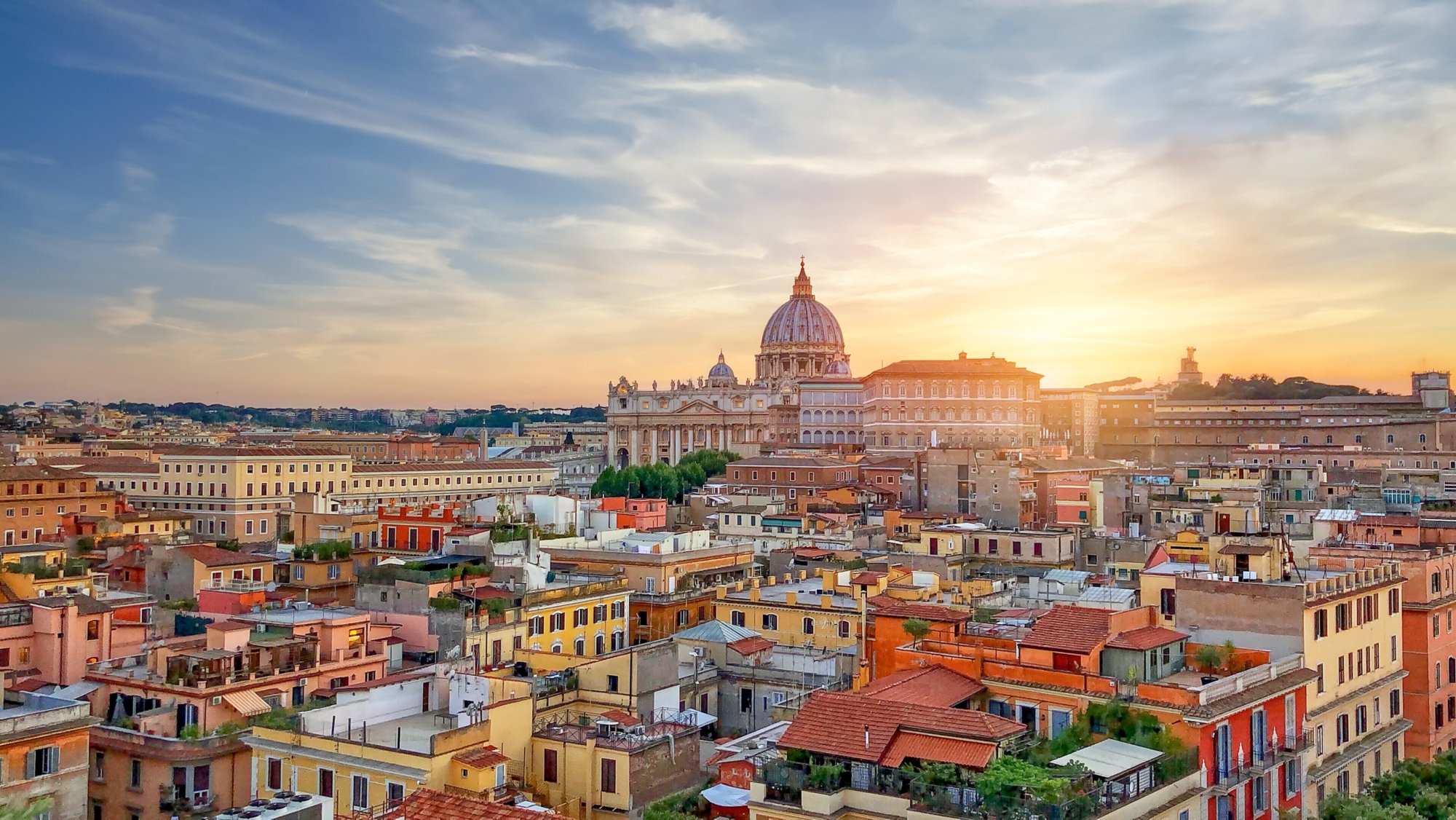 Sunset over the Papal Basilica of Saint Peter and the city buildings in Rome.