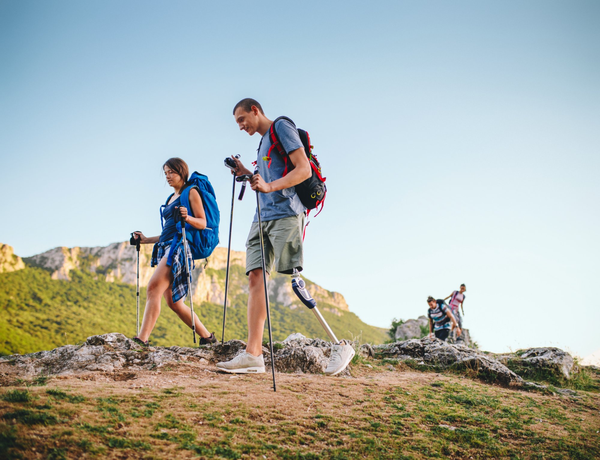 A group of people hiking the mountains, living the healthy lifestyle, with an amputee friend.
