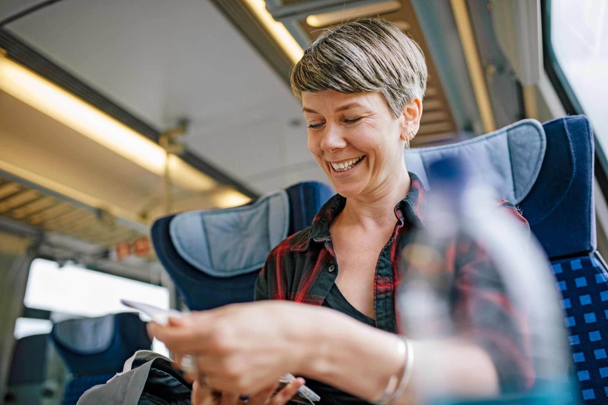 Mature woman traveling on a train, smiling and looking over a map as she plans the rest of the journey.