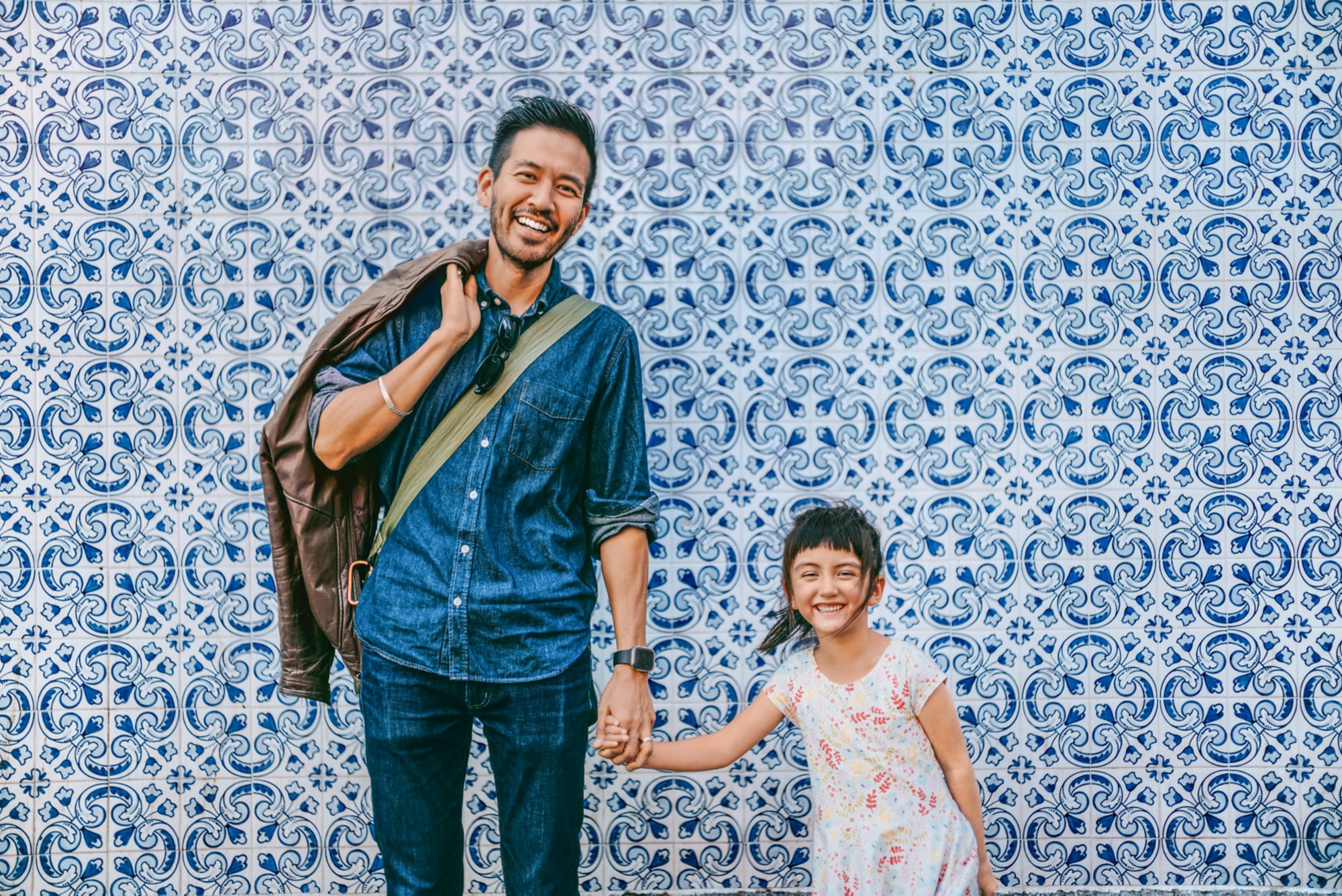 Japanese father and his preschool mixed race daughter on street of Portugal with azulejo tile wall