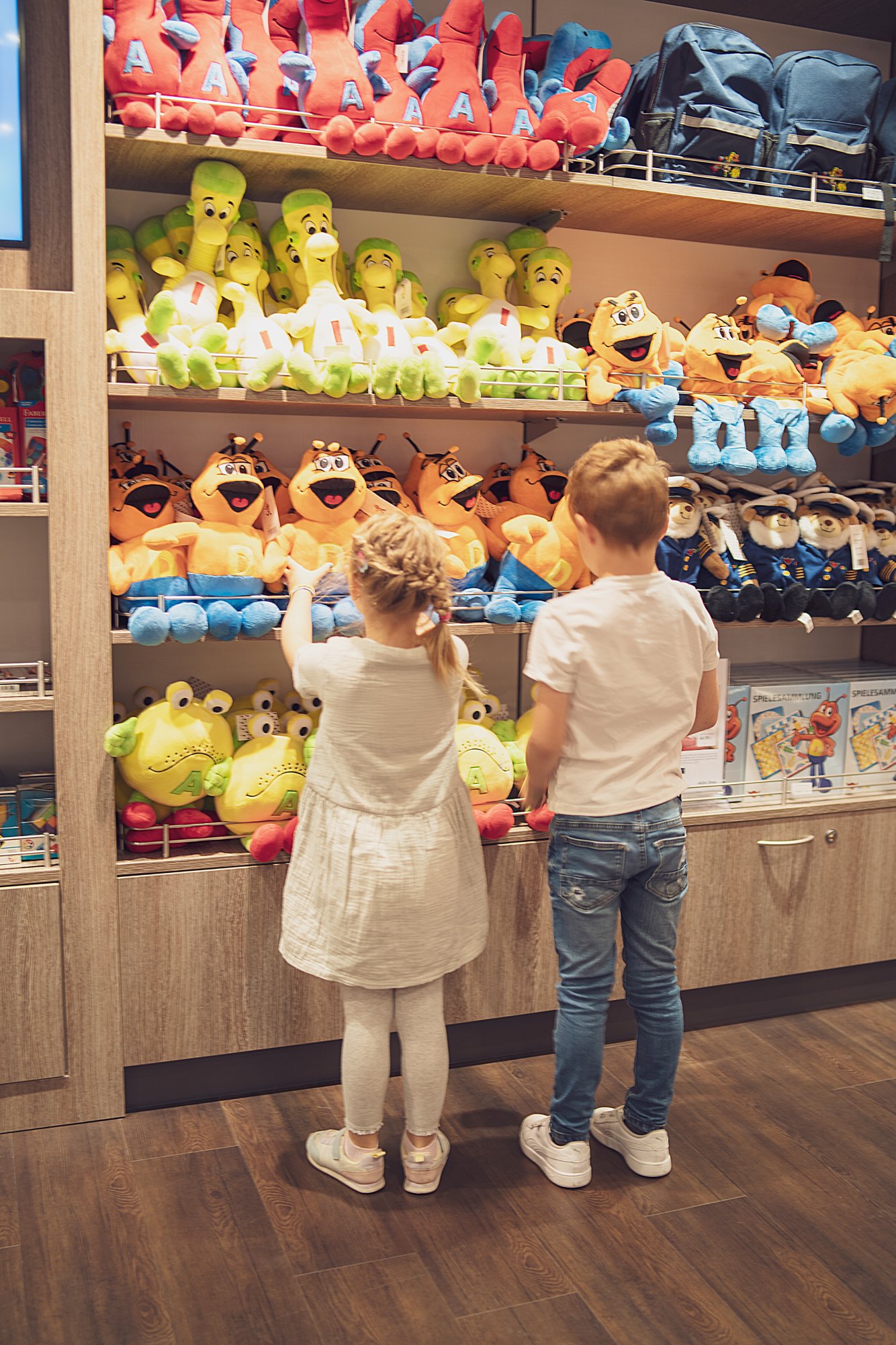 Kinder gucken sich AIDA Kuscheltiere an