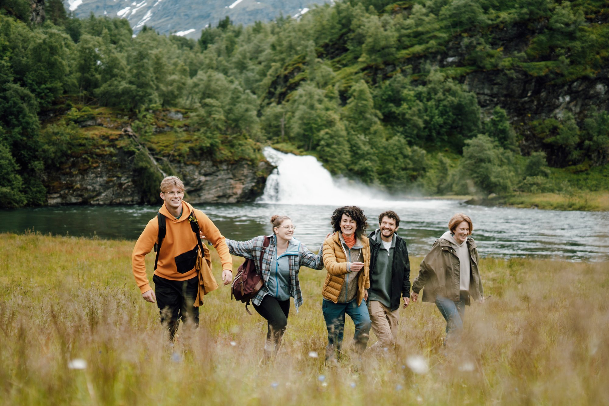 Vier Menschen wandern in Norwegen auf einer Wiese entlang