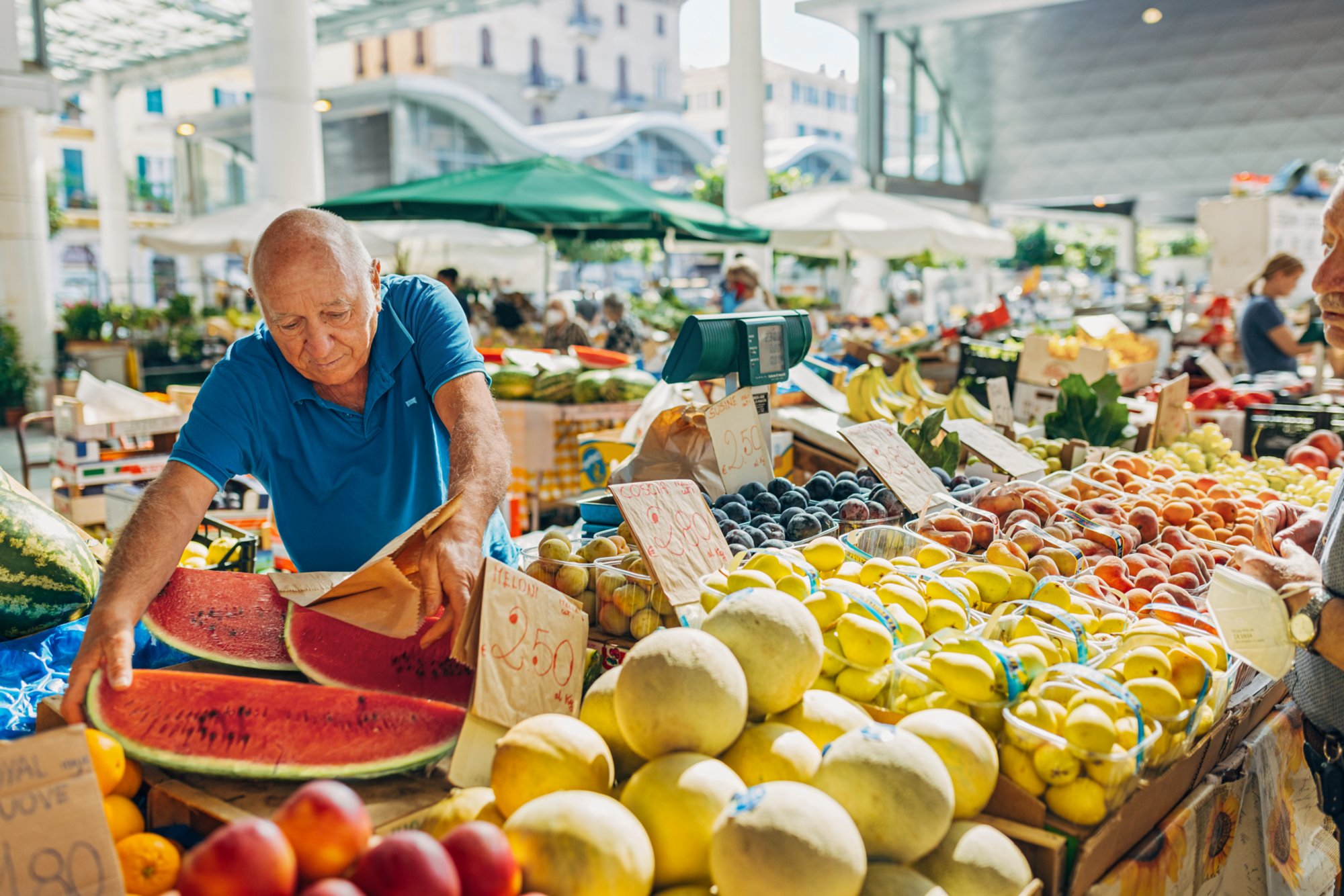 Ein Mann sortiert Gemüse und Obst an einem Marktstand