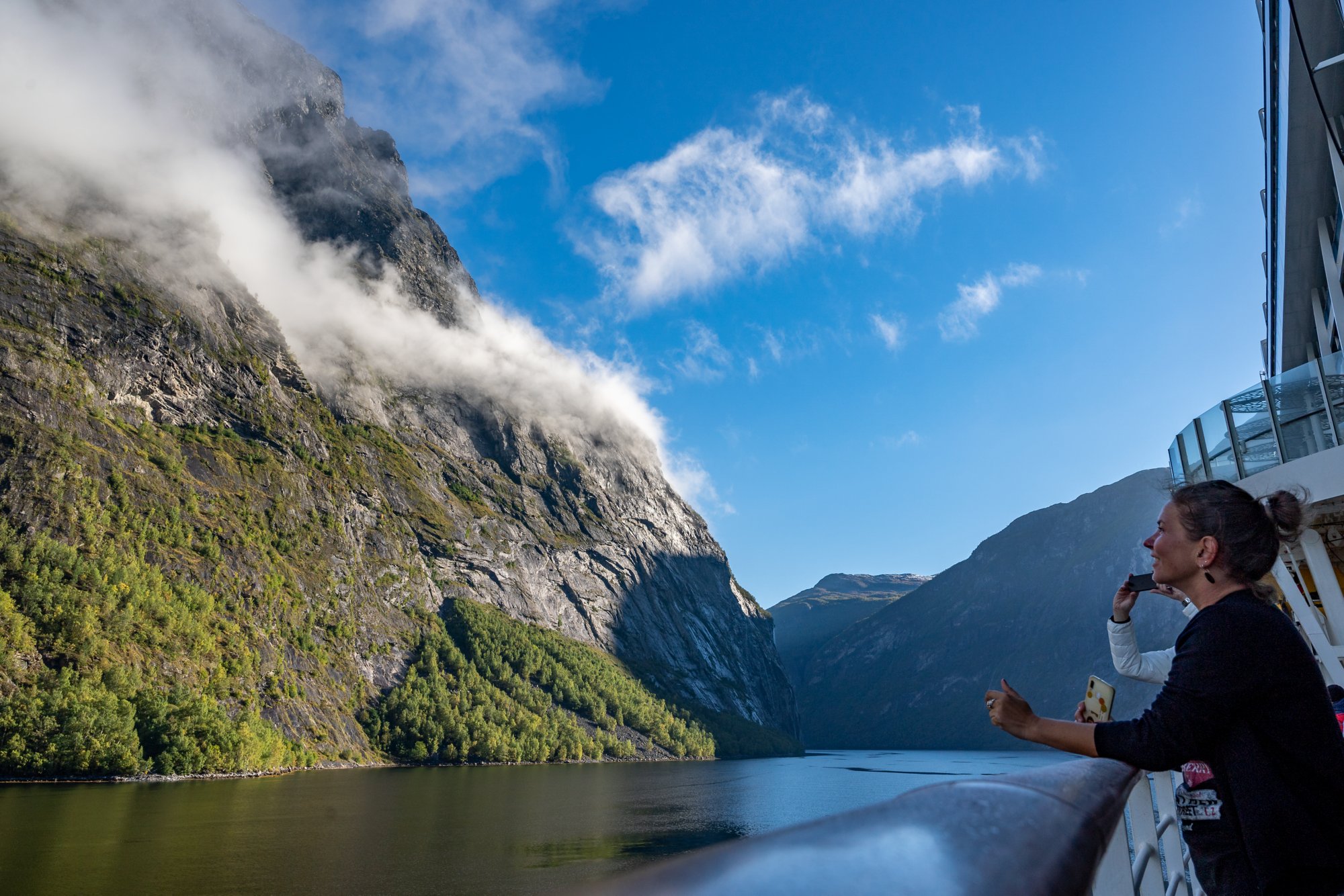 Frau steht an der Reling und blickt auf den Geirangerfjord