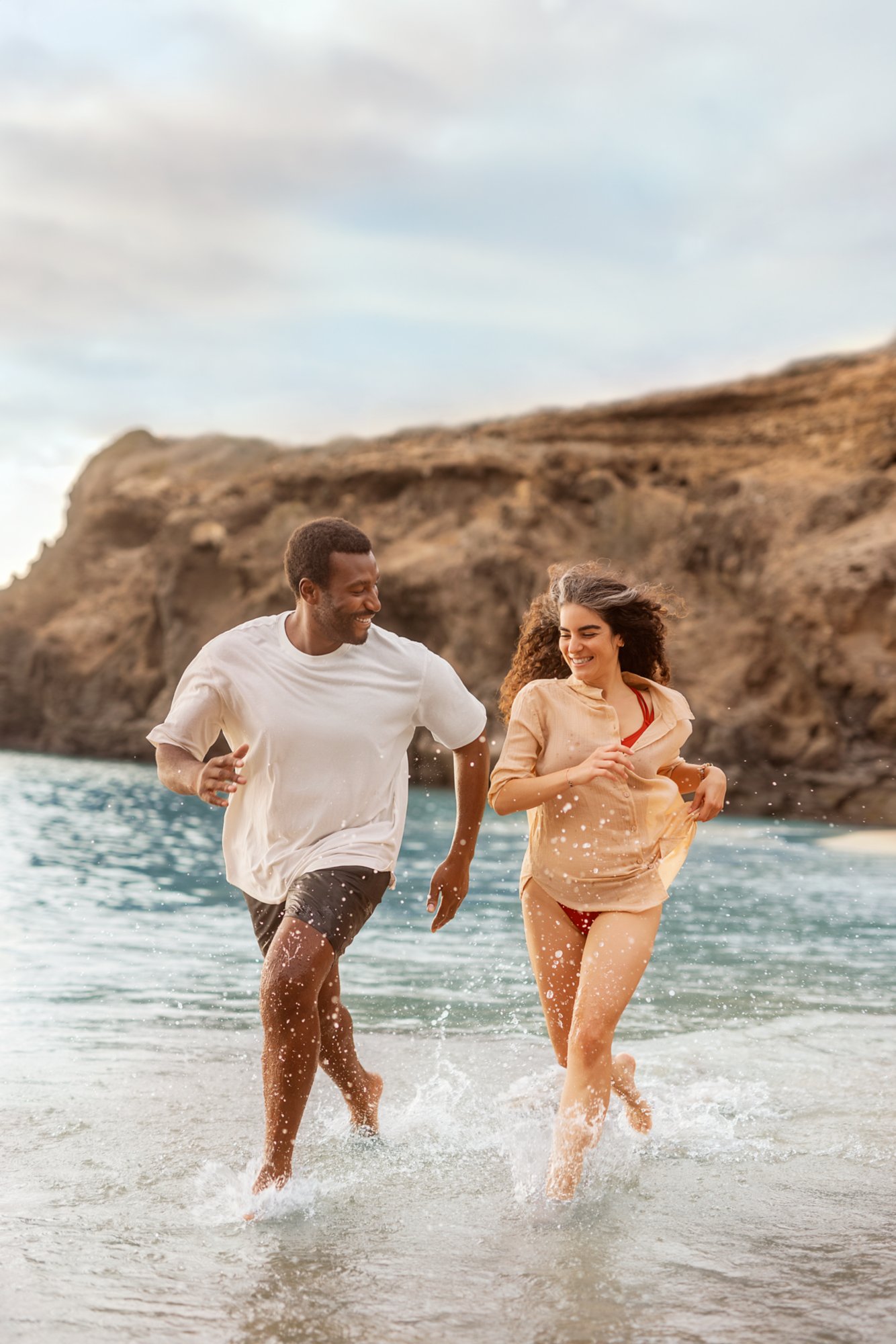 Mann und Frau laufen durch das Wasser am Strand auf Teneriffa