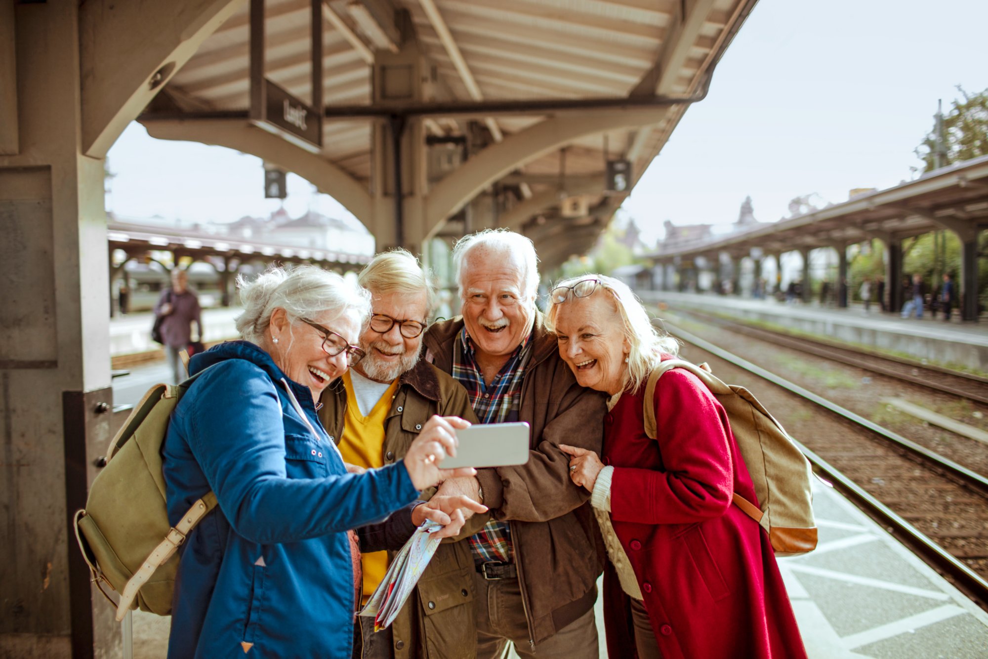 Close up of a group of seniors using their phone at a trainstation