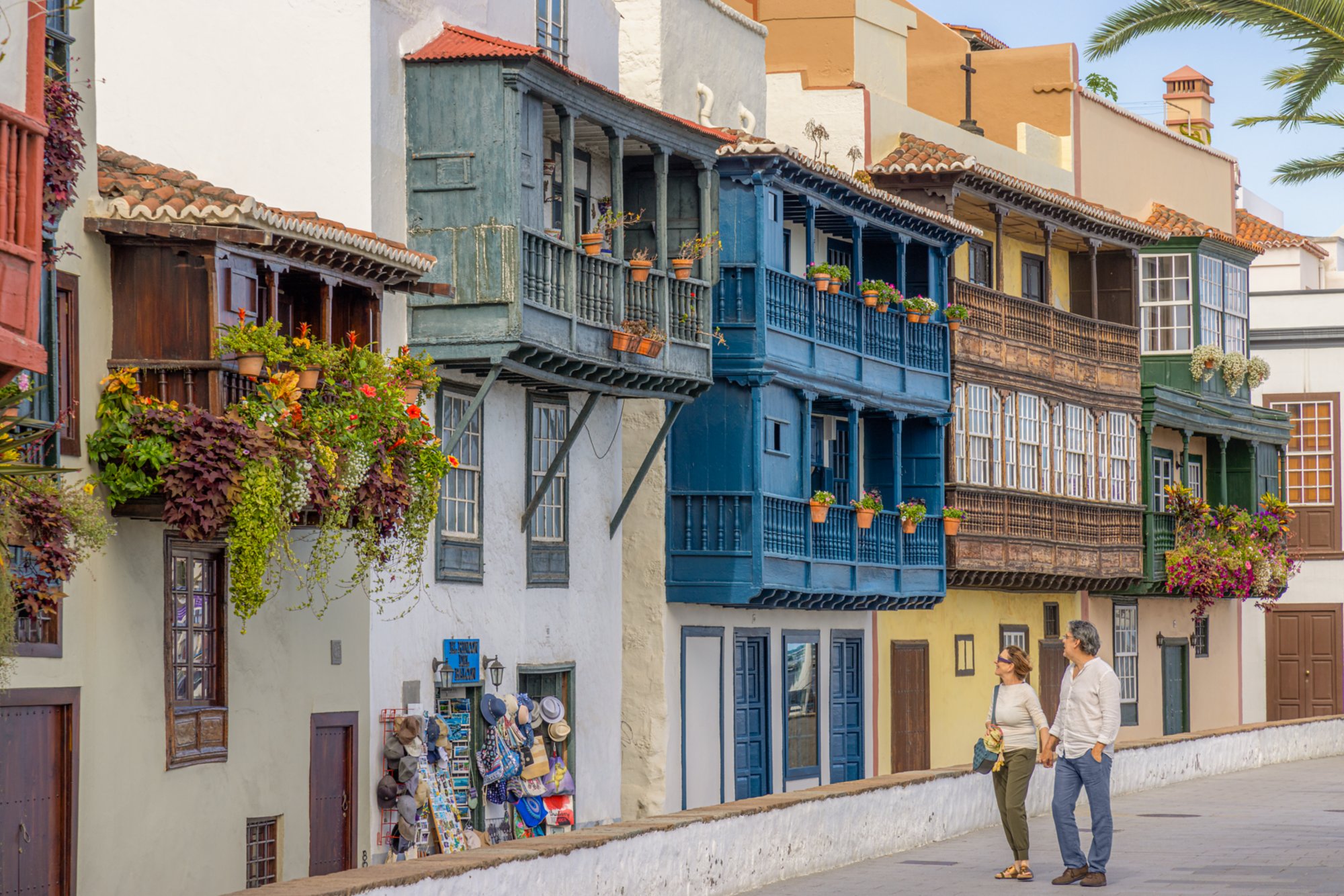 Paar geht vor bunter Häuserreihe spazieren, Santa Cruz, Spanien